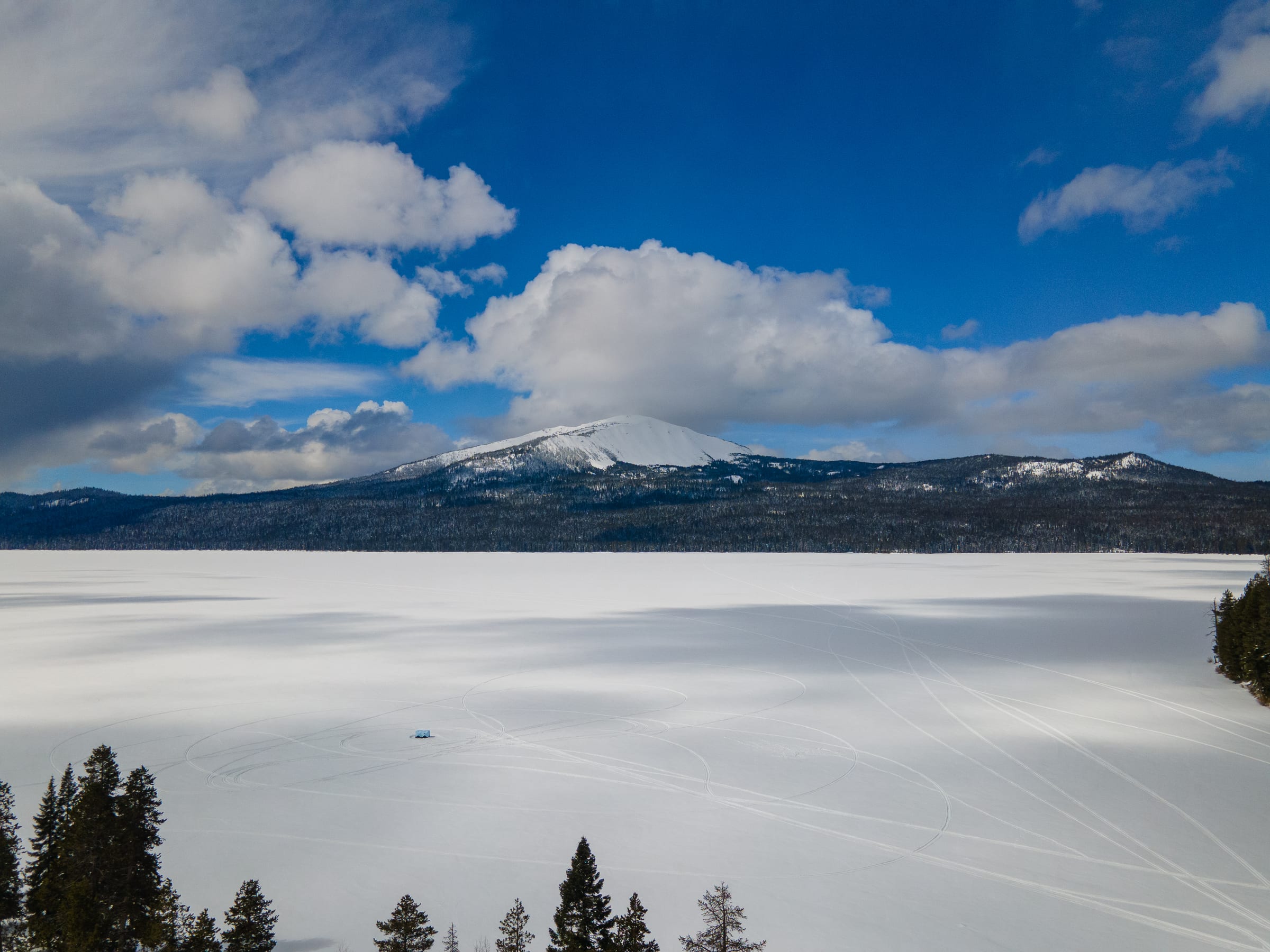 Frozen, snow-covered Diamond Lake under snowy Mount Bailey and a blue March sky