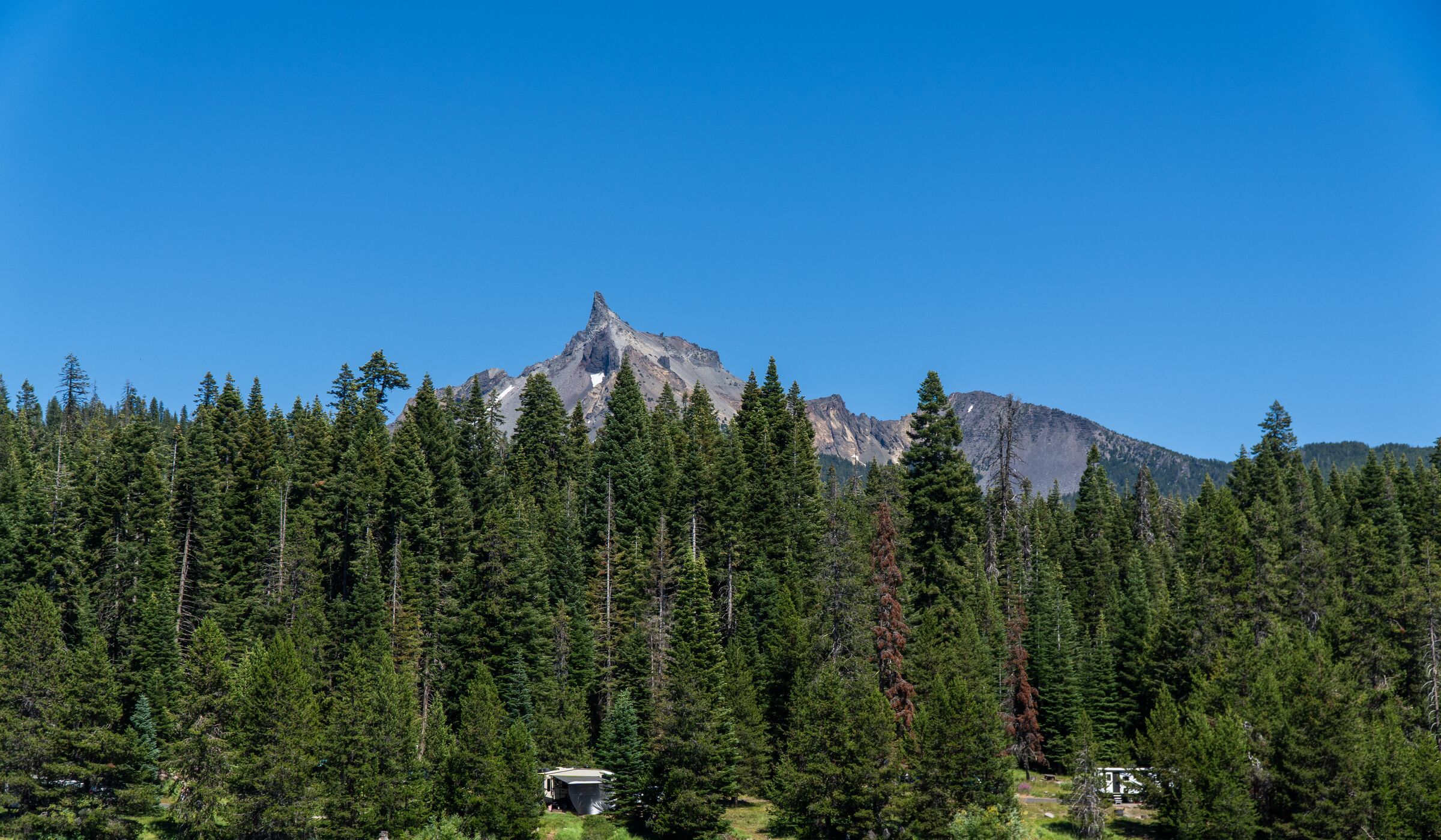 The sharp peak of Mount Thielsen rising above the firs across Diamond Lake in July