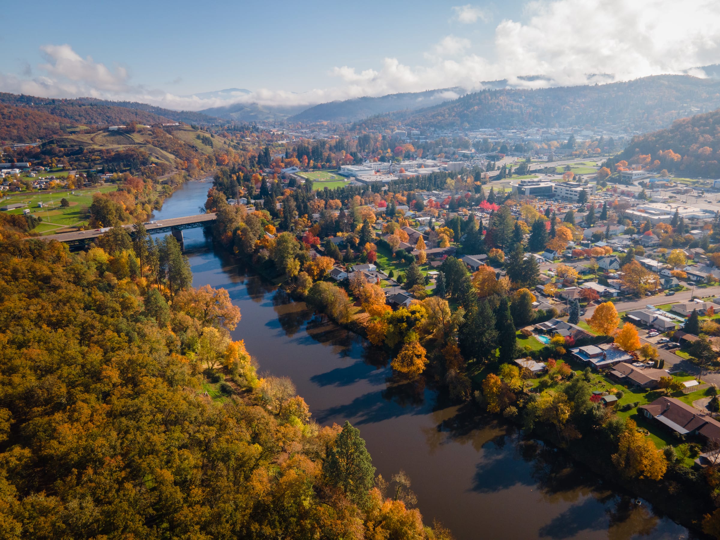 Roseburg from the air in November, the South Umpqua River bending through autumn trees past the town and its bridges
