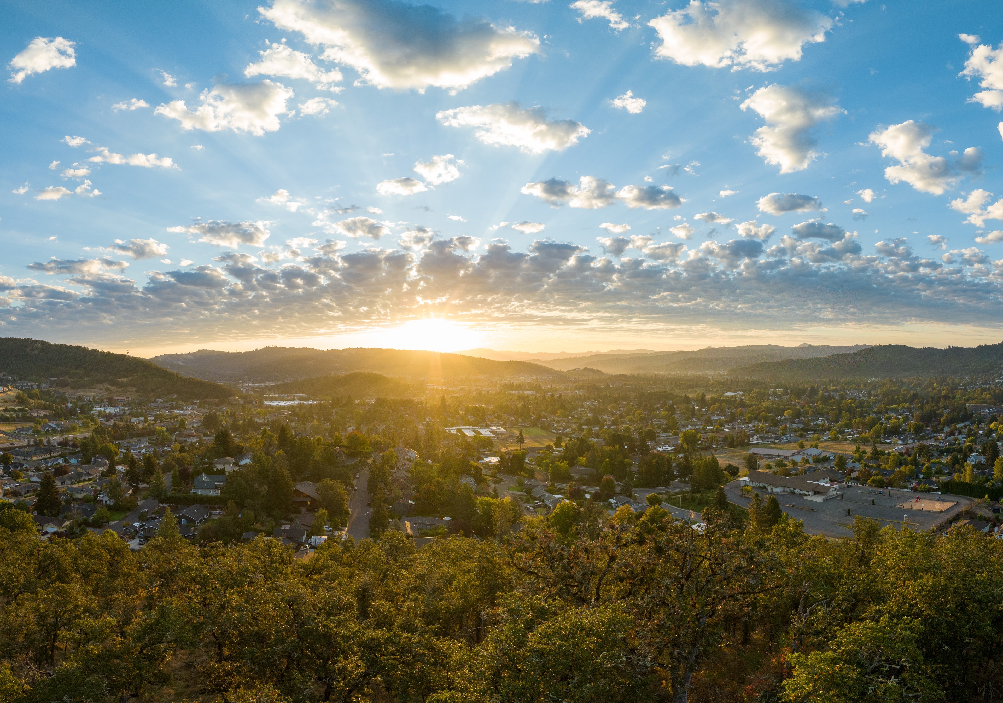 Sunrise over Roseburg in September, the town spread across the valley under a sky of small clouds