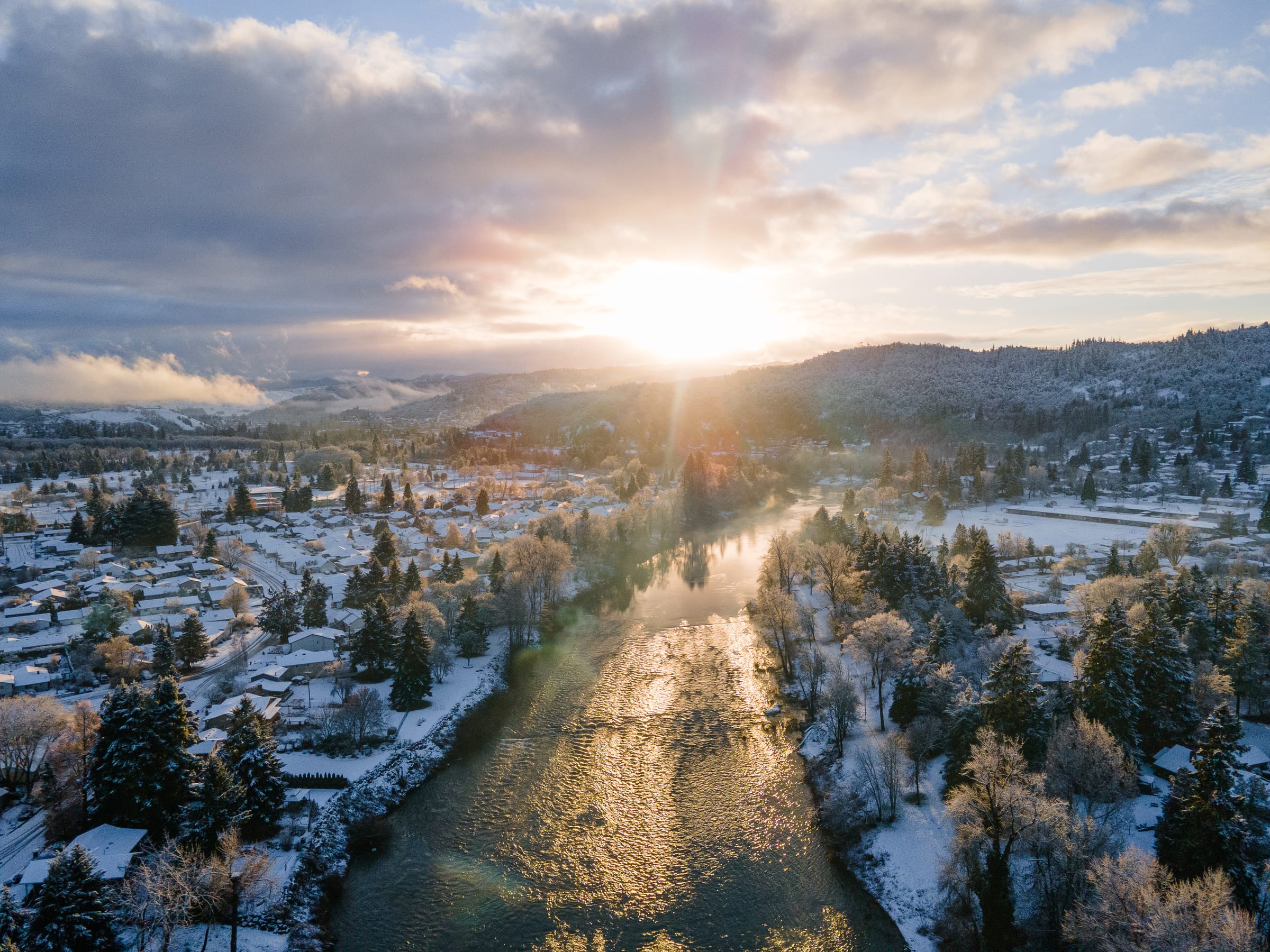 The sun rising over snow-covered rooftops and the South Umpqua River in Roseburg in December