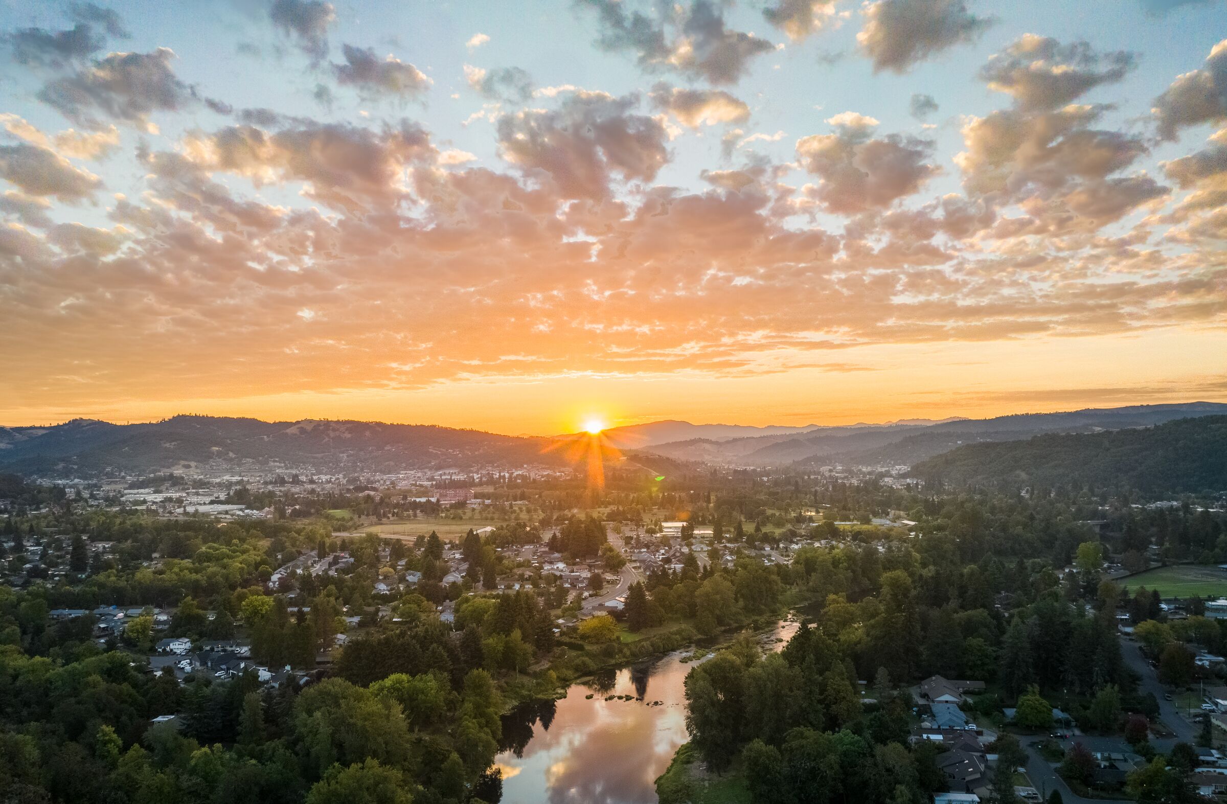 The September sun rising over the hills behind Roseburg, the South Umpqua River reflecting the clouds among the houses and trees below